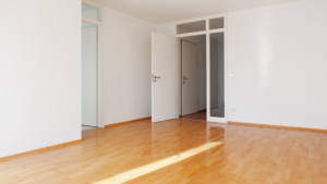 Clean empty apartment building unit with hardwood floors and white walls with sun beaming through the room